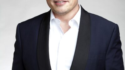 Elon Musk archív portréja sötét zakóban, fehér háttér előtt