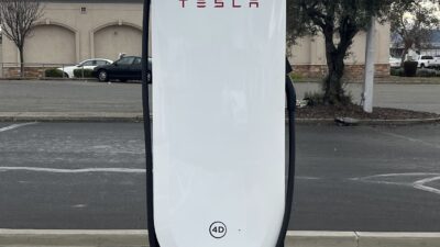 Tesla Supercharger V4 töltőoszlop fehér burkolattal és piros felirattal